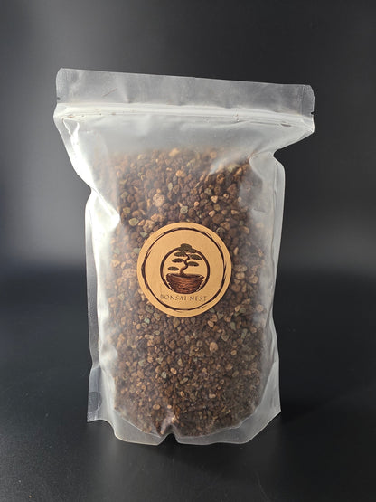 Flat sealed pouch of greyish-brown, evenly coarse granules, round wooden Bonsai Nest label centred on the clear plastic.