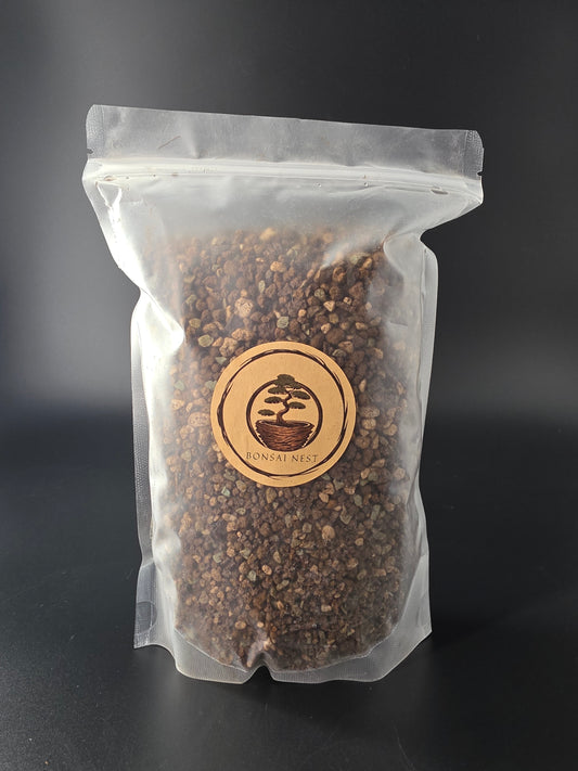 Flat sealed pouch of greyish-brown, evenly coarse granules, round wooden Bonsai Nest label centred on the clear plastic.