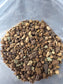 Close-up of chunky granules in tan, brown and pale grey-green piled on the crinkled clear plastic of the bag.